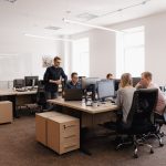 Full concentration at work. Group of young business people working and communicating while sitting at the office desk together with colleagues sitting in the background
